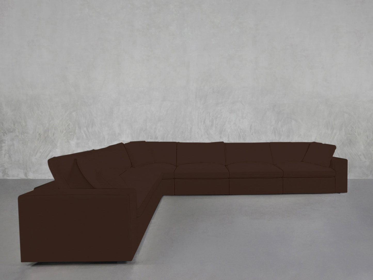 A 6-Seat Modular Corner Sectional in dark brown is placed against a light gray textured wall on a gray floor in a minimal, empty room.