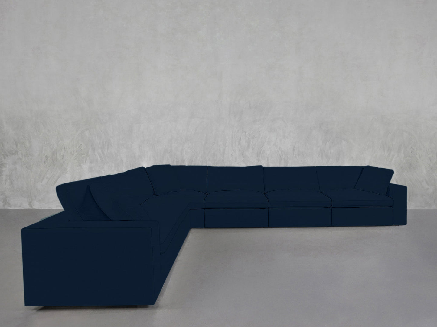 A 6-Seat Modular Corner Sectional in dark blue is placed against a plain, light gray textured wall and floor in a minimalist, empty room.