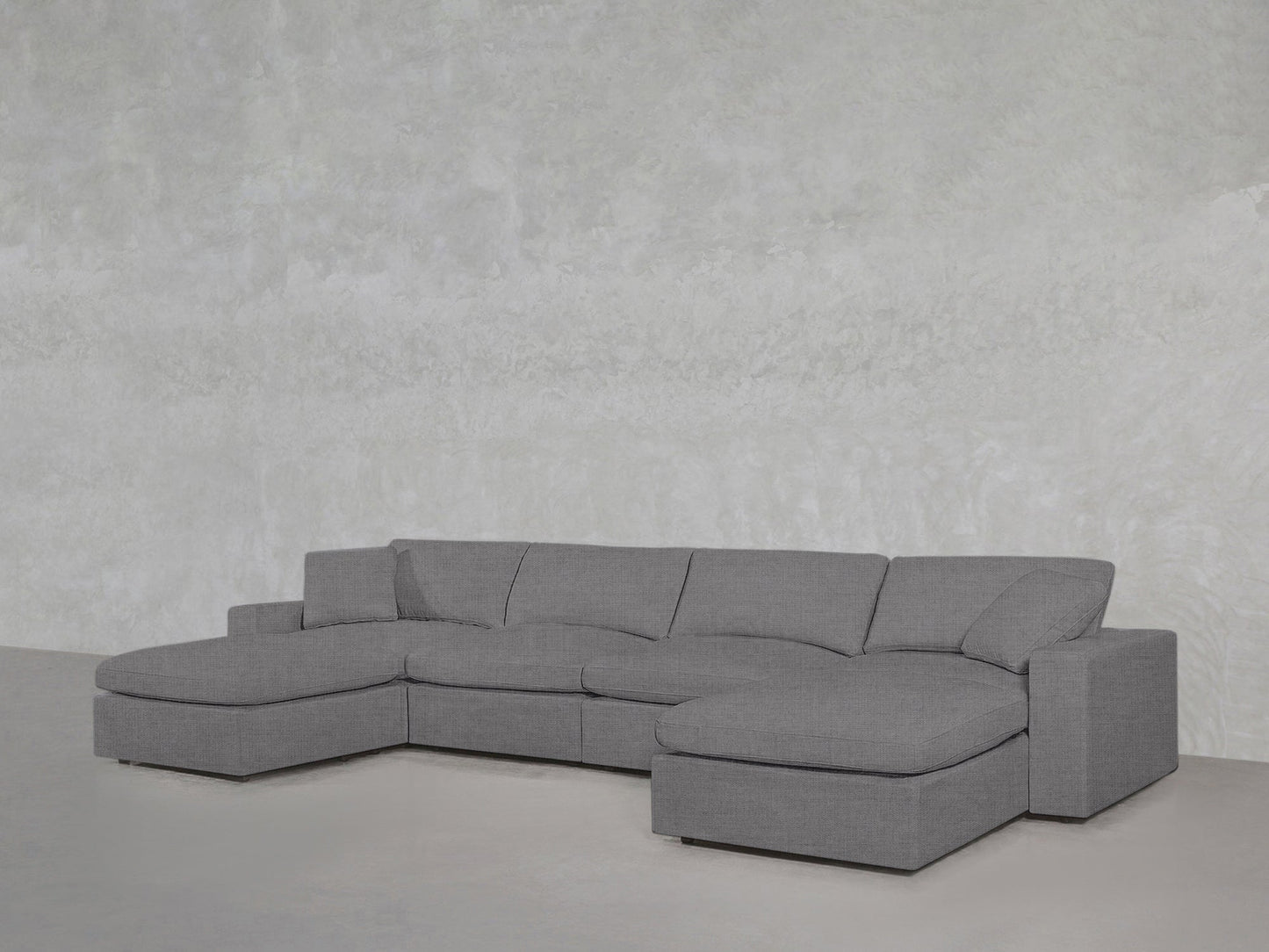 A 6-Seat Modular Double Chaise Sectional in modern gray sits against a light gray textured wall and floor, creating a minimalist, contemporary setting.