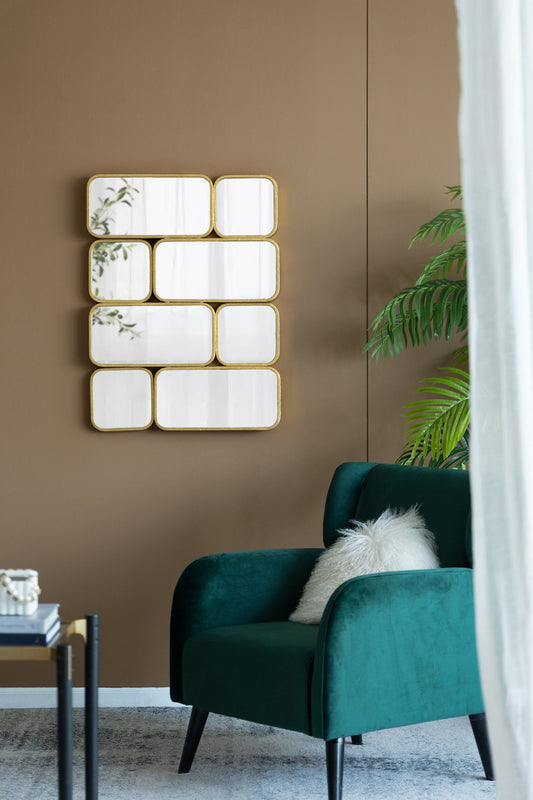 A modern living room features a green velvet armchair, white furry pillow, small table, potted plant, and a gold Mirror With en Metal Framed Decorative Rectangle Mirror for bedroom, hallway, or living space on a brown wall.
