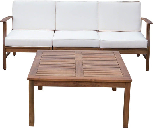 The Perla 3 Seater Sofa and Table Set features a wooden patio sofa with white cushions, positioned behind a matching rectangular wooden coffee table with a slatted top.
