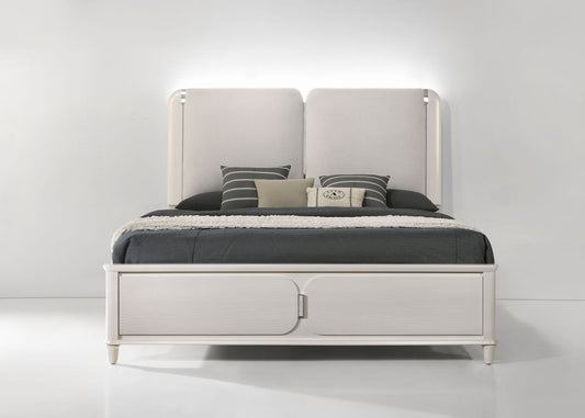 The Laveda - Boucle Bed With LED features a modern white design with a tall upholstered headboard, black and gray bedding, and decorative pillows, set against a plain white wall in a minimalistic room.