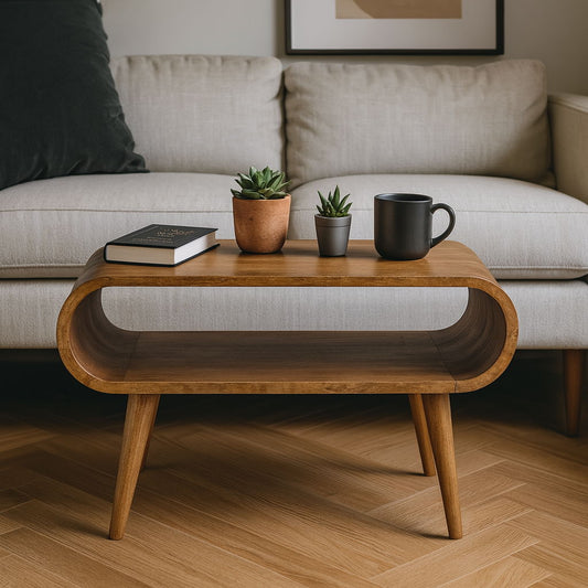 The Solid Wood Open Coffee Table with rounded edges holds two potted succulents, a closed book, and a black mug. Behind it is a light-colored sofa set on a wooden floor.