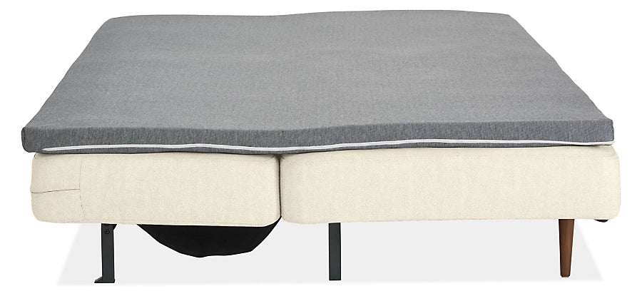 The Deco Convertible Sleeper Sofa is fully extended, showcasing a light-colored base with a grey mattress on top and supported by metal legs.