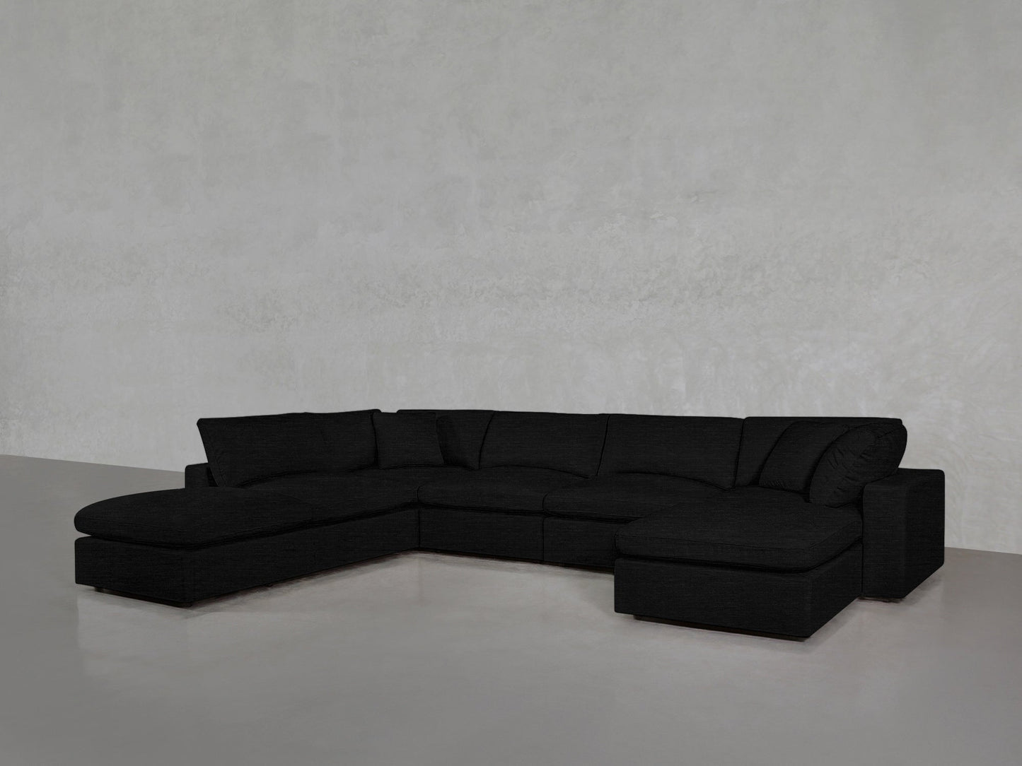 A 7-Seat Modular Chaise Corner Lounger Sectional in modern black sits on a light gray polished floor against a plain, textured gray wall.