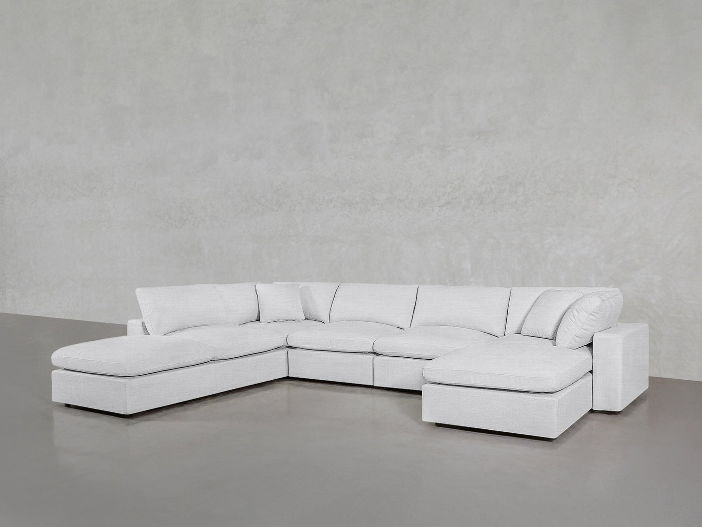 The 7-Seat Modular Chaise Corner Lounger Sectional in light gray features an L-shape, wide seats, multiple cushions, and sits on a shiny gray floor against a textured light gray wall.