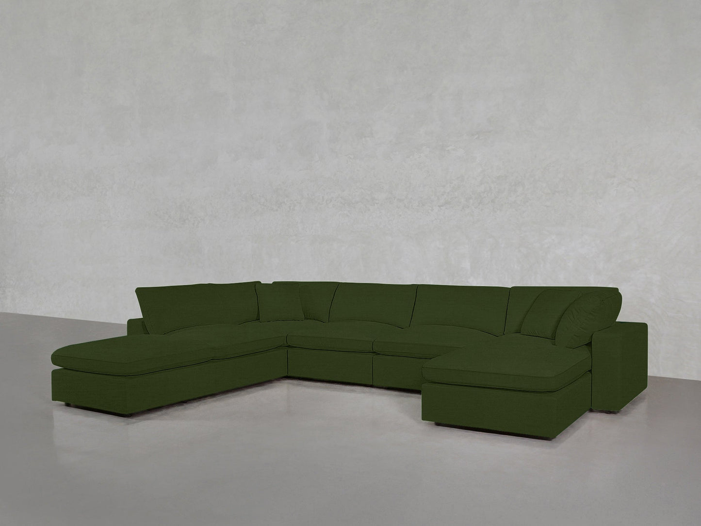 A spacious, dark green 7-Seat Modular Chaise Corner Lounger Sectional with a chaise at each end sits in a minimalist room featuring light gray walls and a smooth gray floor.