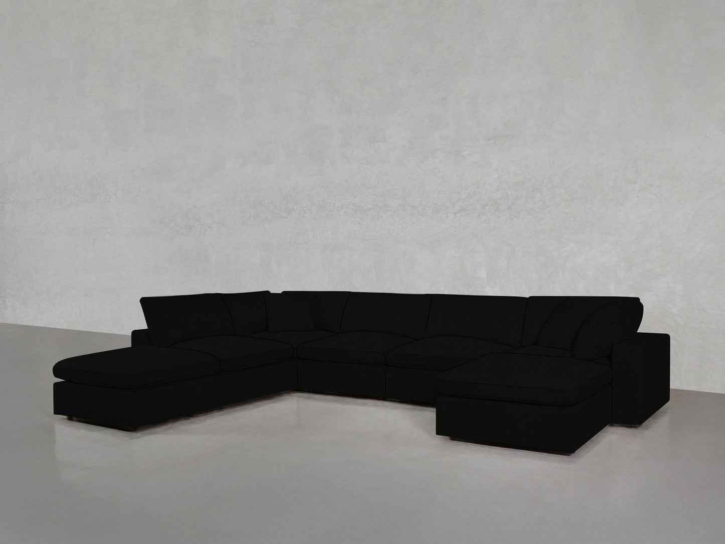 A spacious black 7-Seat Modular Chaise Corner Lounger Sectional with wide seats and no visible legs, placed against a plain light gray wall and floor.