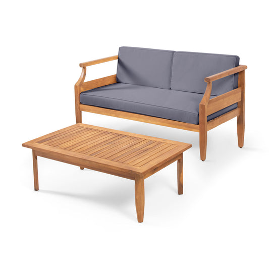 The Aston 2 Piece Wood Outdoor Patio Conversation Seating Set with Cushions features a wooden loveseat with gray cushions and a matching rectangular coffee table, both displayed against a white background.