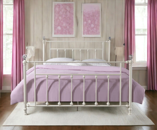 The Comet Bed, featuring an elegant spindle design, is topped with a lavender bedspread and white pillows, placed on a light rug in a bedroom with pale wood walls, pink curtains, and two pink abstract paintings above.
