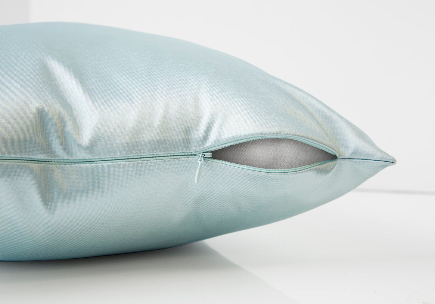 A close-up of a light blue square decorative throw pillow with hypoallergenic insert visible through a partially open zipper, set against a plain white background. Modern design, insert included.