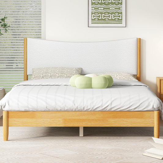 A modern bedroom showcases a Queen Size Rubber Wooden Bed with a Teddy Velvet Cushion Upholstered Headboard in natural finish, gray and white bedding, soft green and white pillows, a geometric rug, and framed abstract artwork.