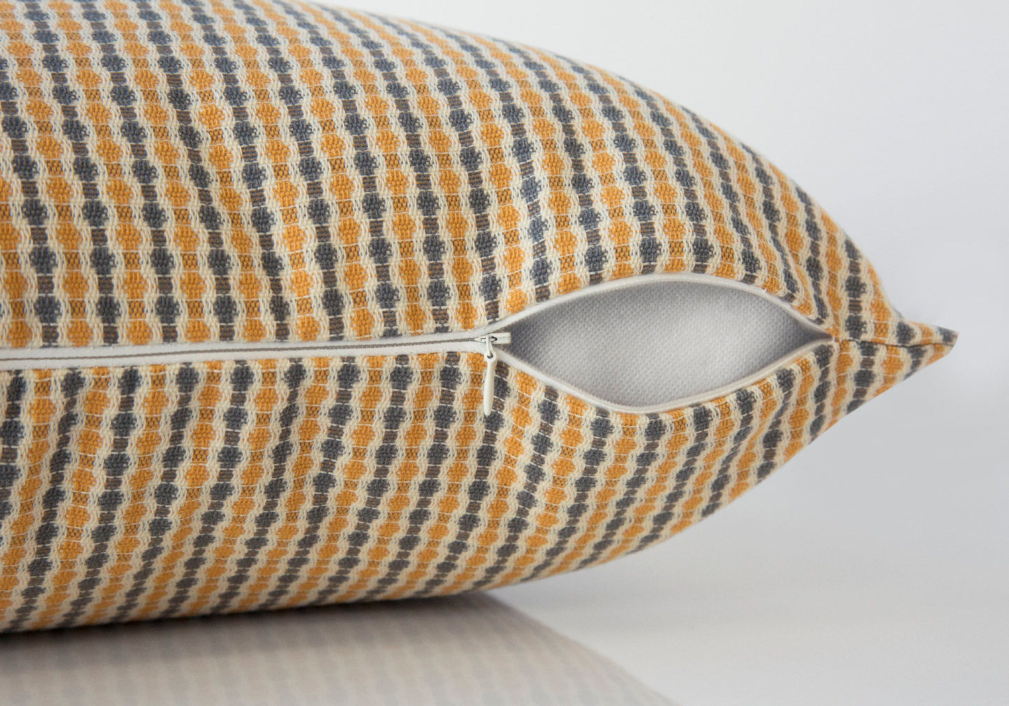 A close-up of a Square Decorative Throw Pillow with a yellow, gray, and white dotted pattern, showing the partially open white zipper and inner fabric. Hypoallergenic insert included.