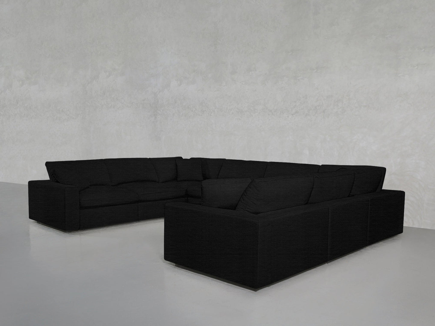 An 8-Seat Modular U-Sectional with a modern black design and clean lines sits in an empty room featuring light gray walls and a smooth, reflective gray floor.