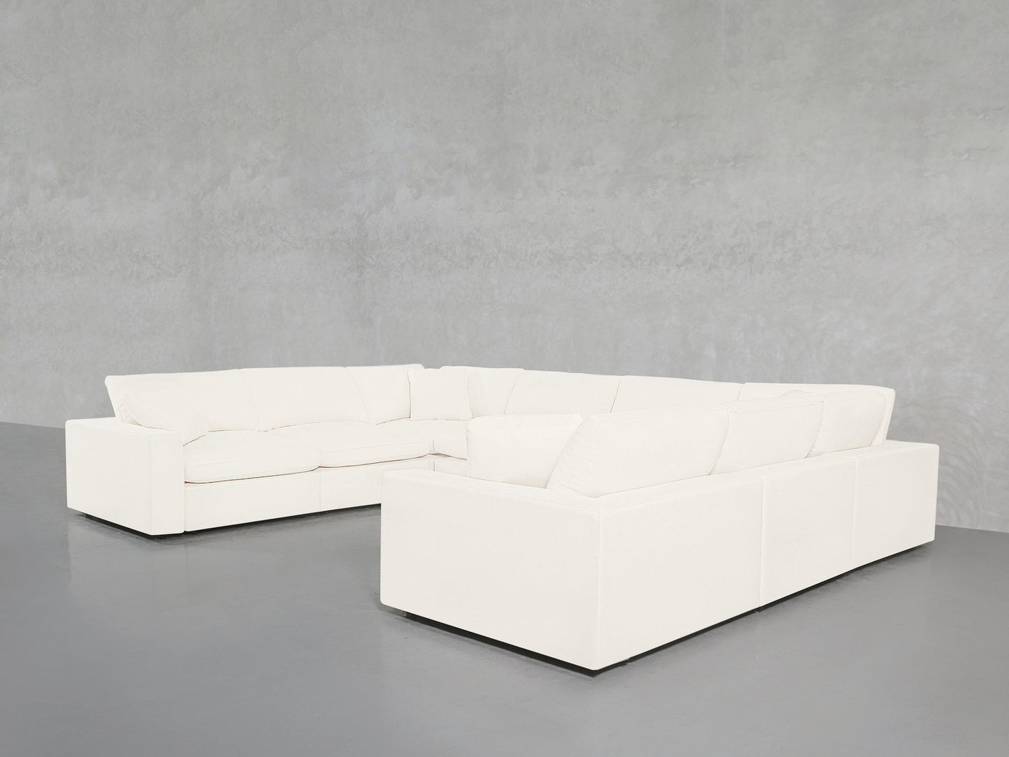 An 8-Seat Modular U-Sectional with a modern white design and clean lines sits on a smooth gray floor against a light gray textured wall.