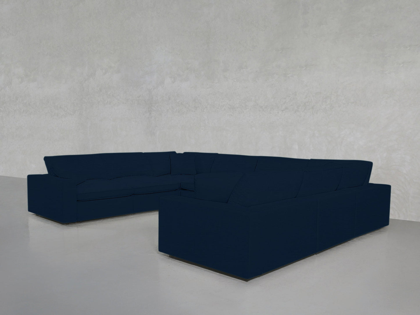 An 8-Seat Modular U-Sectional in dark blue rests on a light gray floor against a plain light gray wall, creating a minimalist atmosphere.