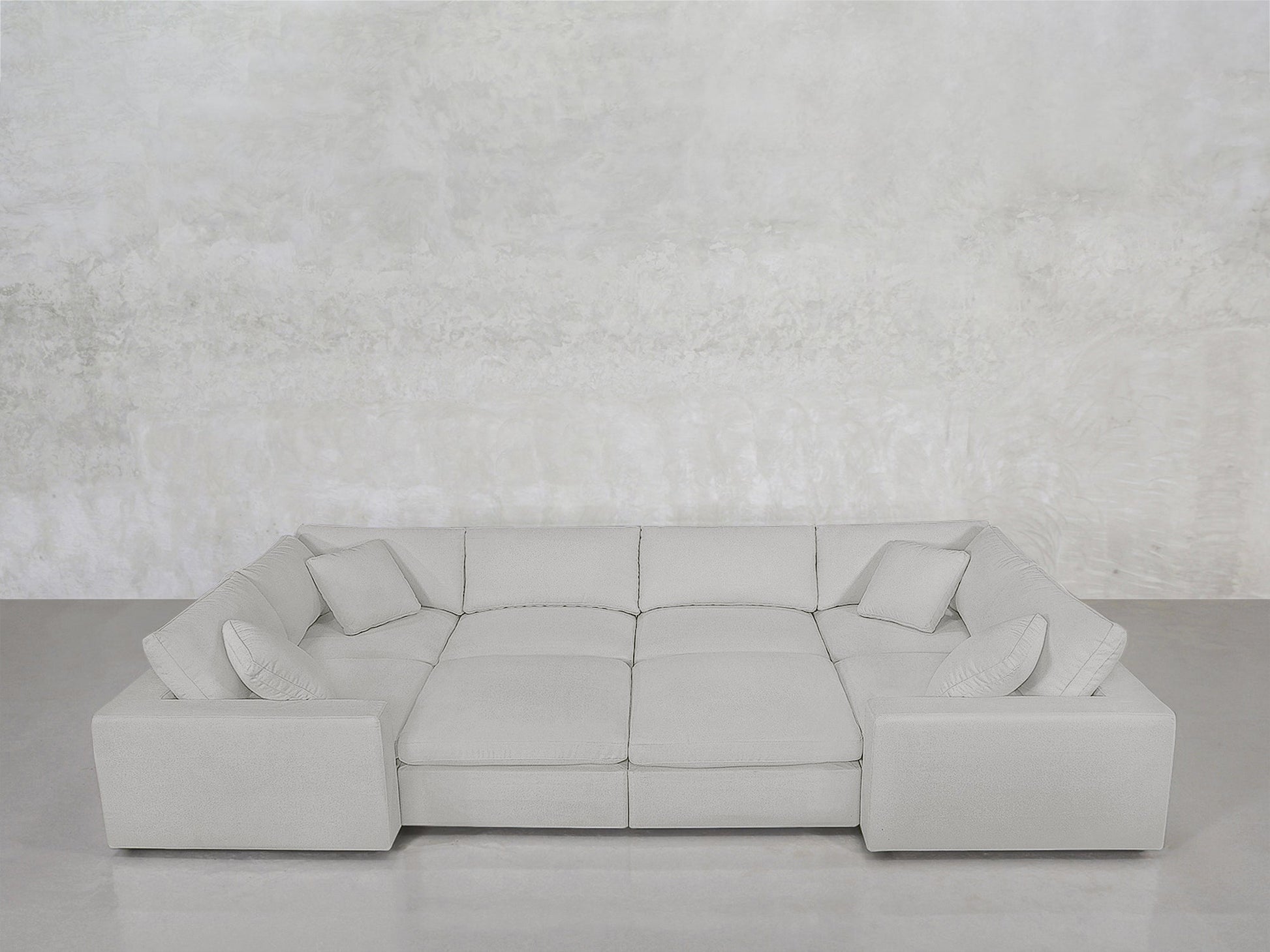 The 8-Seat Modular Closed Pit, in light gray with four matching cushions, is arranged against a plain textured light gray wall and a smooth gray floor.