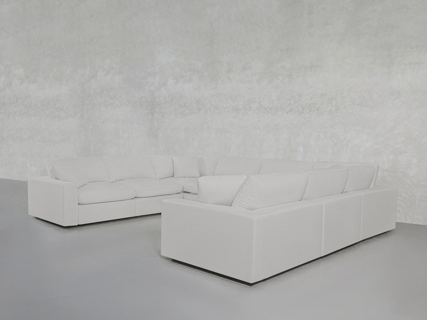 The 8-Seat Modular U-Sectional, featuring clean lines and plush cushions in light gray, is set against a minimalist, textured light gray wall and floor.