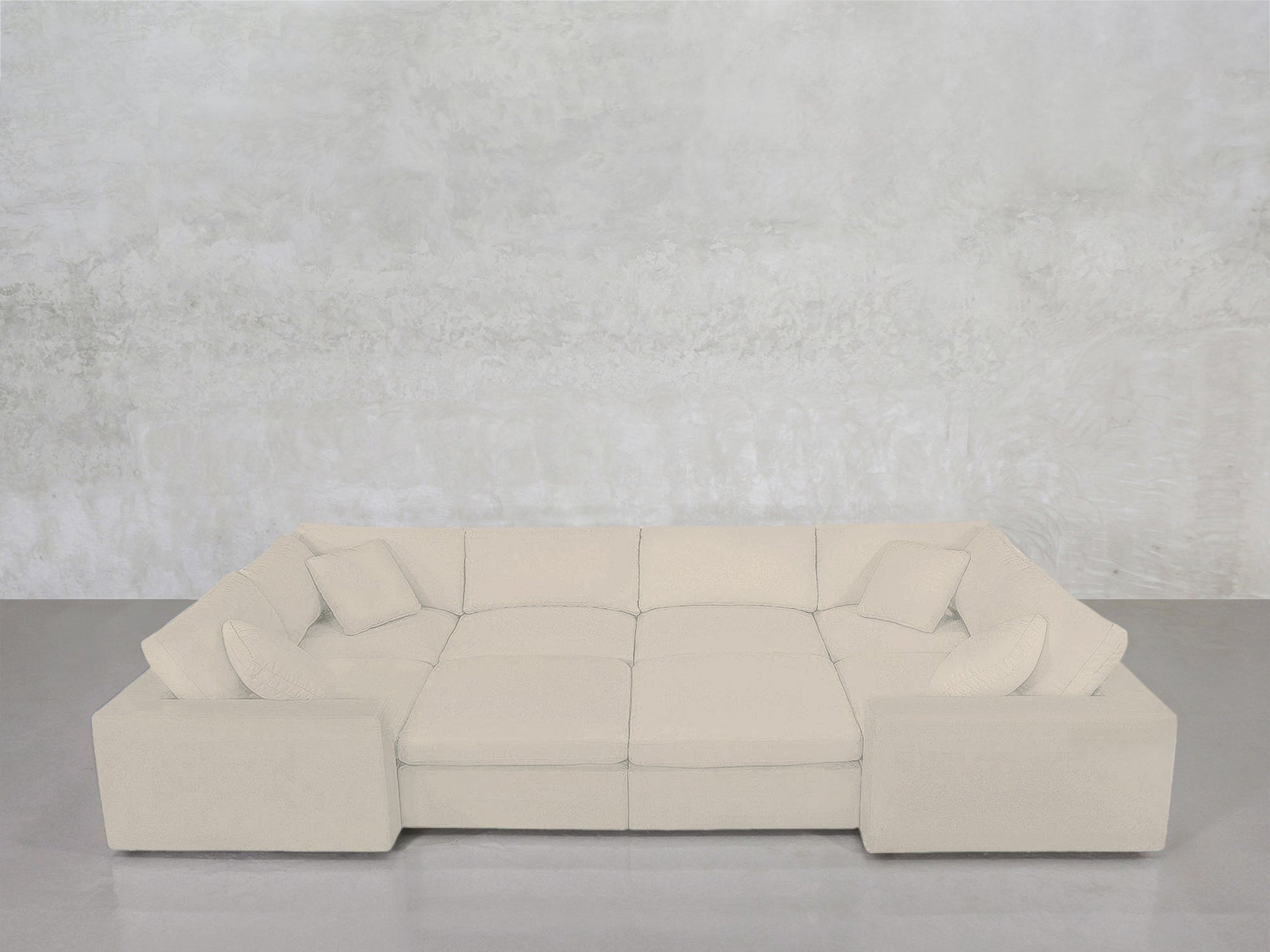 An 8-Seat Modular Closed Pit in beige, paired with four matching cushions, is arranged in a U-shape against a light gray textured wall and concrete floor.