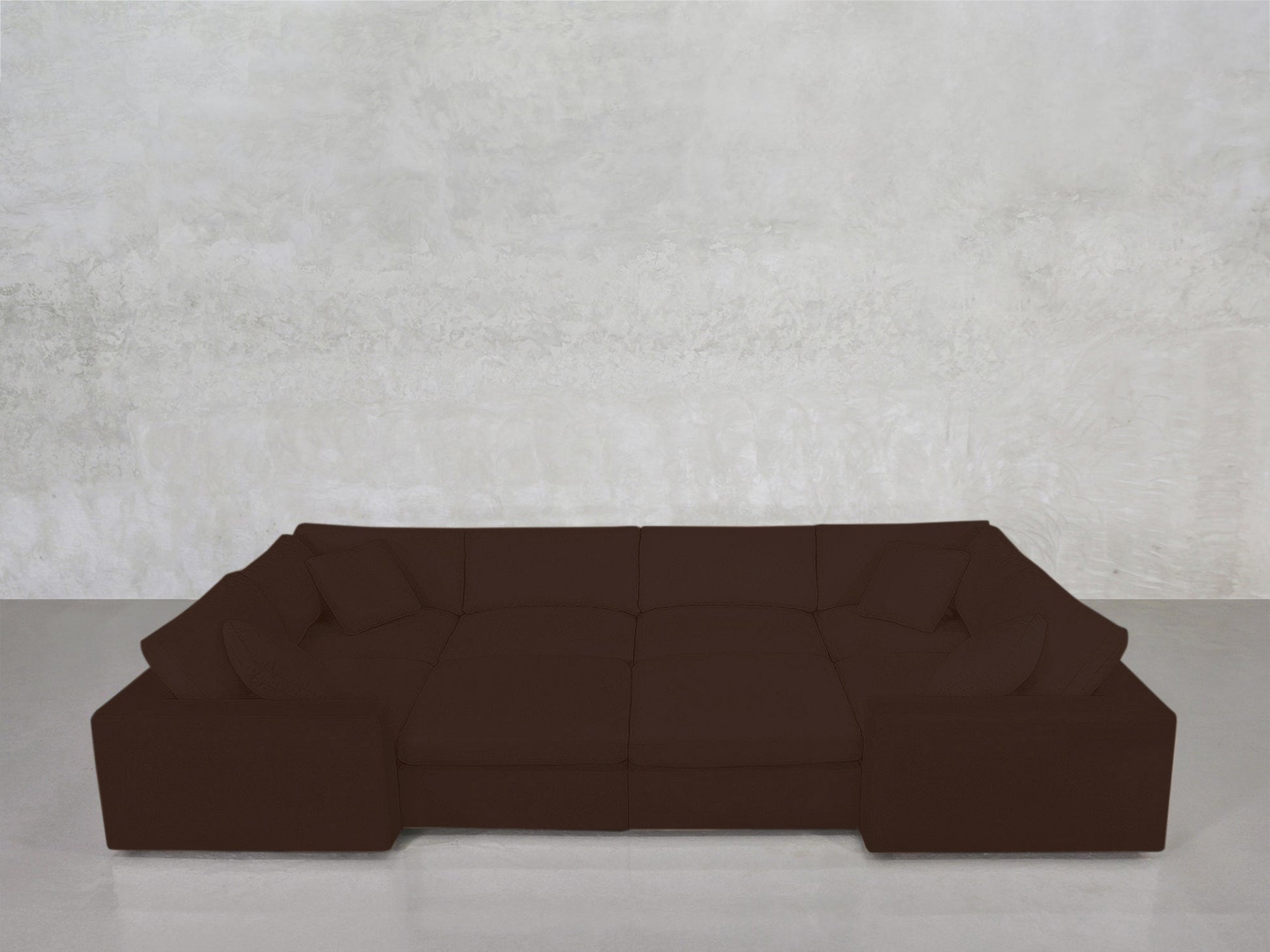 An 8-Seat Modular Closed Pit in dark brown with wide armrests and four matching cushions is set against a textured light gray wall on a smooth gray floor.