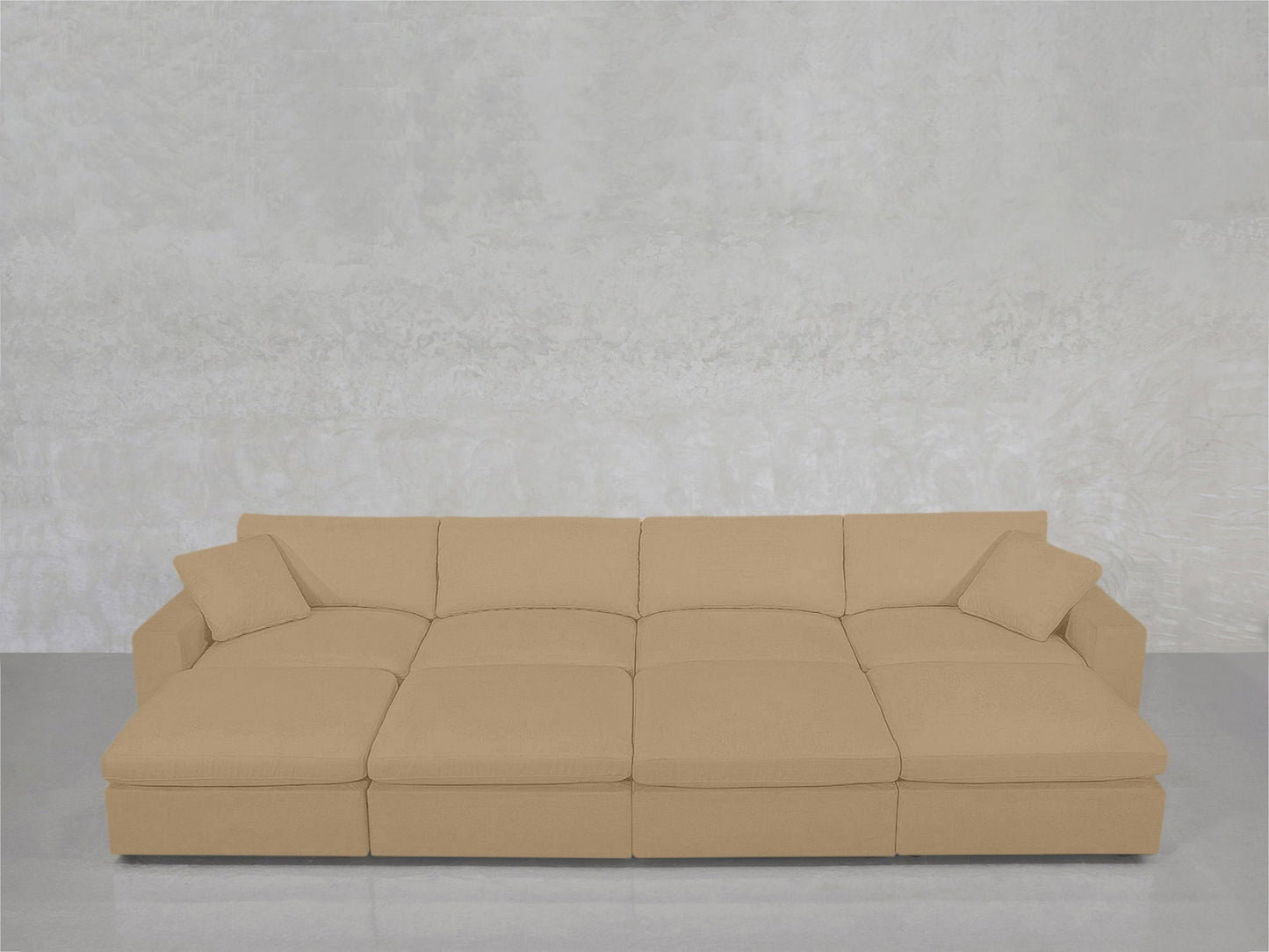 An 8-Seat Modular Daybed in beige with matching cushions is set against a light gray textured wall on a shiny floor.