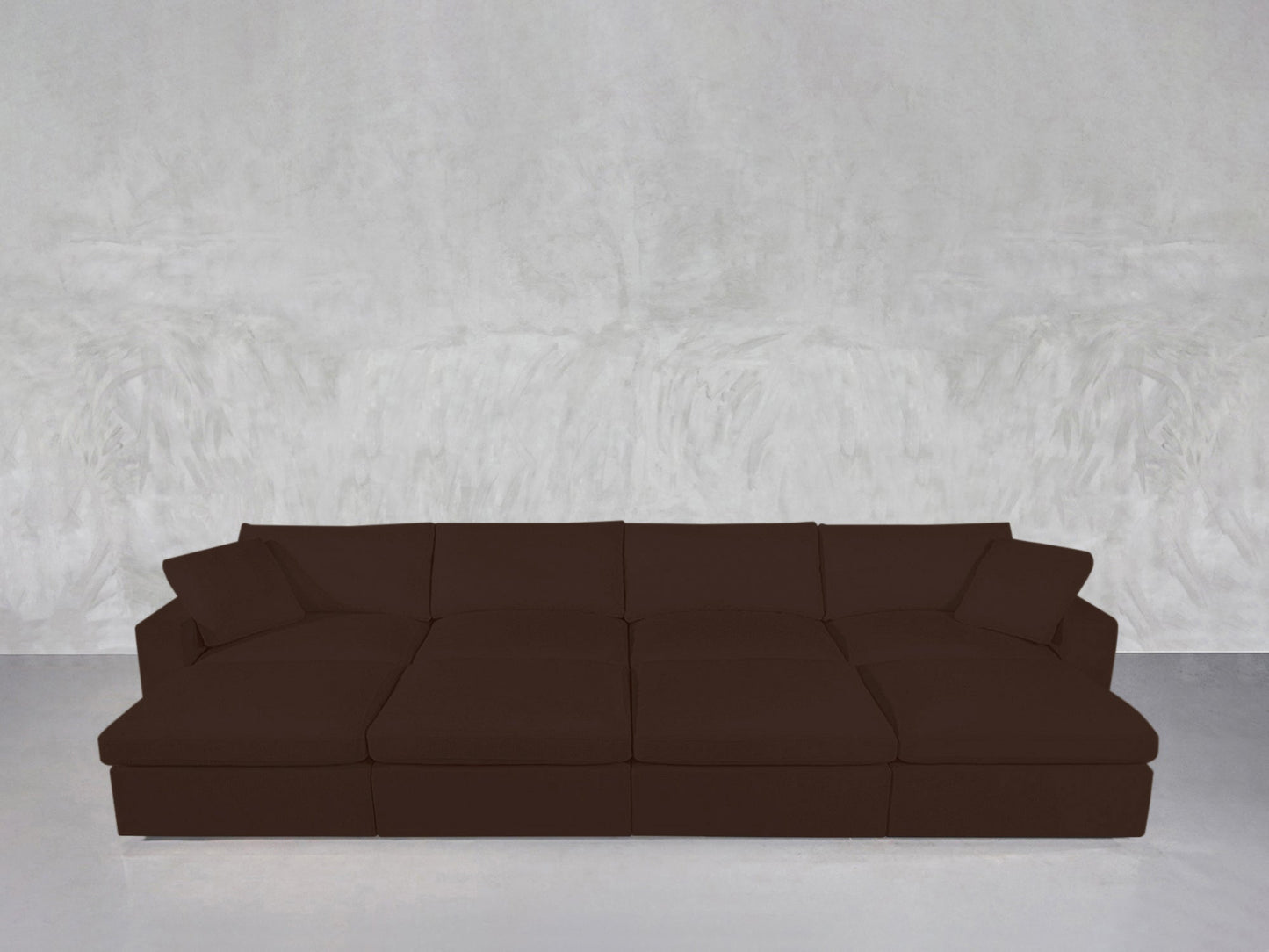 An 8-Seat Modular Daybed with cushions and armrests is placed against a light gray, textured wall on a smooth, light-colored floor.