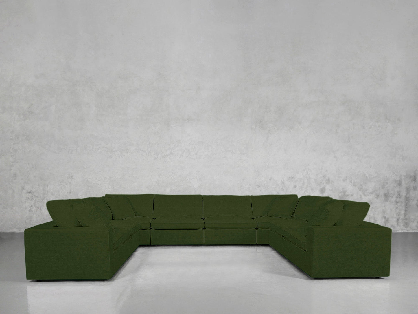 An 8-Seat Modular U-Sectional with a modern design, upholstered in dark green, is arranged in a U-shape against a plain light gray textured wall and a smooth, light-colored floor.
