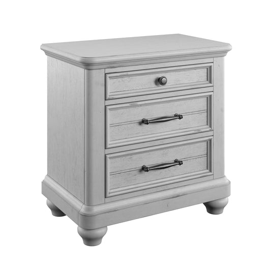 The Mariano 3 Drawer Nightstand With USB in gray features decorative handles, rounded feet, and three drawers: the top with a round knob and the two lower drawers with horizontal handles.