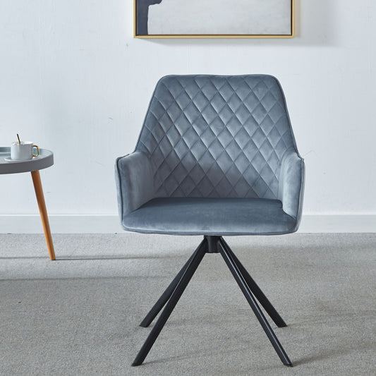 A Modern Desk Chair No Wheel, upholstered in blue with ergonomic design and metal legs, sits on a light gray carpet. To its left is a small round table with a coffee cup, and framed artwork hangs on the white wall behind.