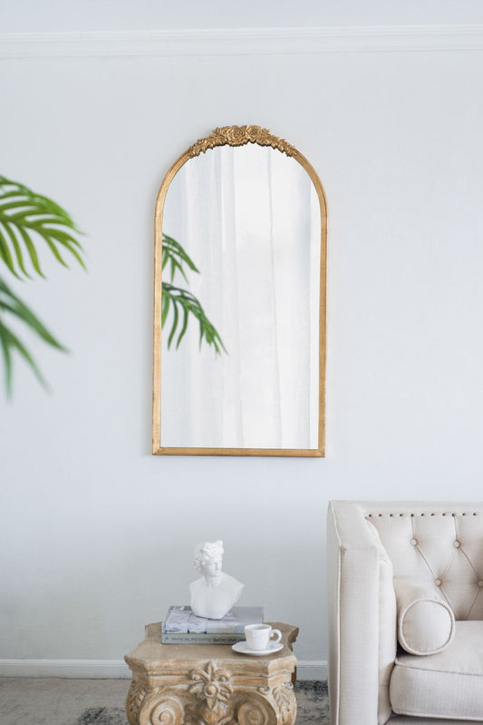 A Wood Floor Mirror, Full Body Mirror for Dressing and Makeup, stands on a white wall above a decorative table with a bust, books, and teacup; a beige tufted sofa and a green plant are also in the room.