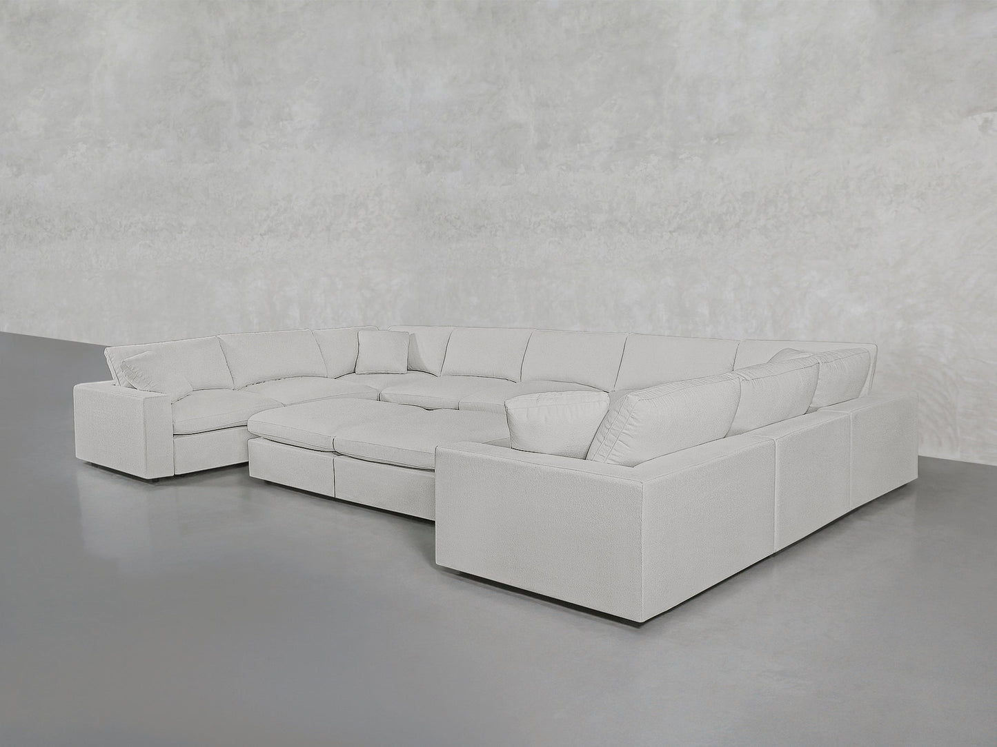 A spacious 9-Seat Modular U-Sectional with Double Ottoman in light gray features plush cushions, arranged in a U-shape on a smooth gray floor against a textured light gray wall.
