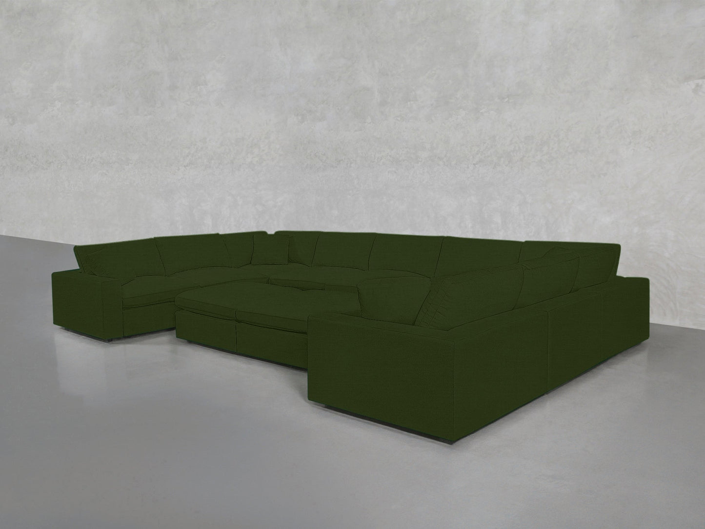 A spacious 9-Seat Modular U-Sectional with Double Ottoman in dark green and thick cushions sits in a modern, empty room with light gray walls and a smooth gray floor.