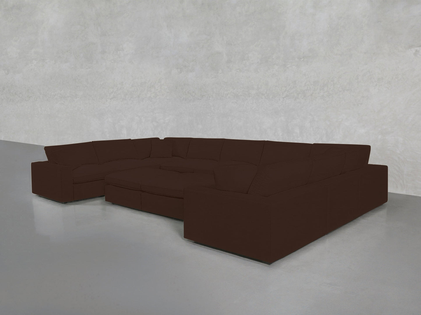 A 9-Seat Modular U-Sectional with Double Ottoman in dark brown is arranged on a smooth gray floor against a plain, light gray textured wall.