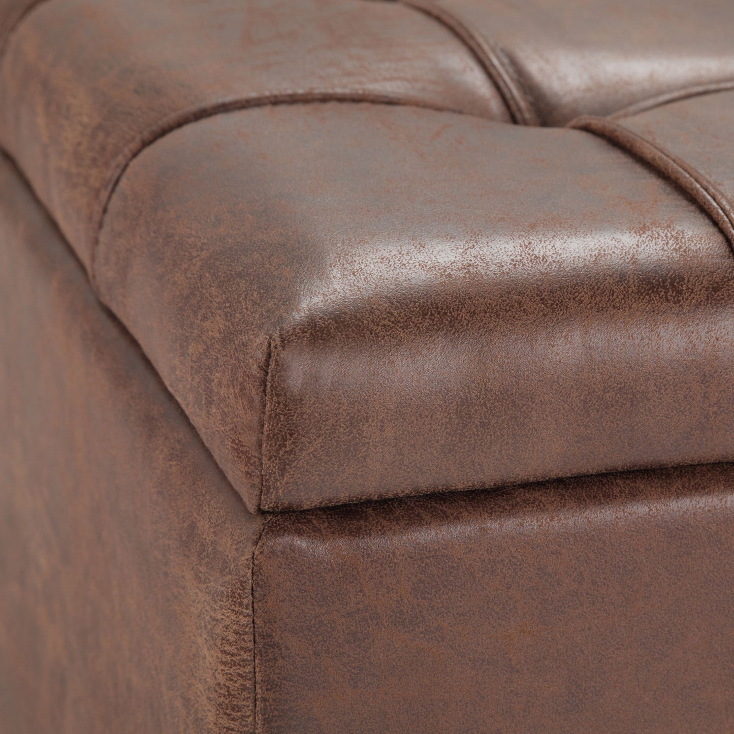 Close-up of the Harrison - Upholstered Coffee Table Storage Ottoman, featuring brown leather with visible stitched seams and a tufted, cushioned surface for a smooth, vintage look.