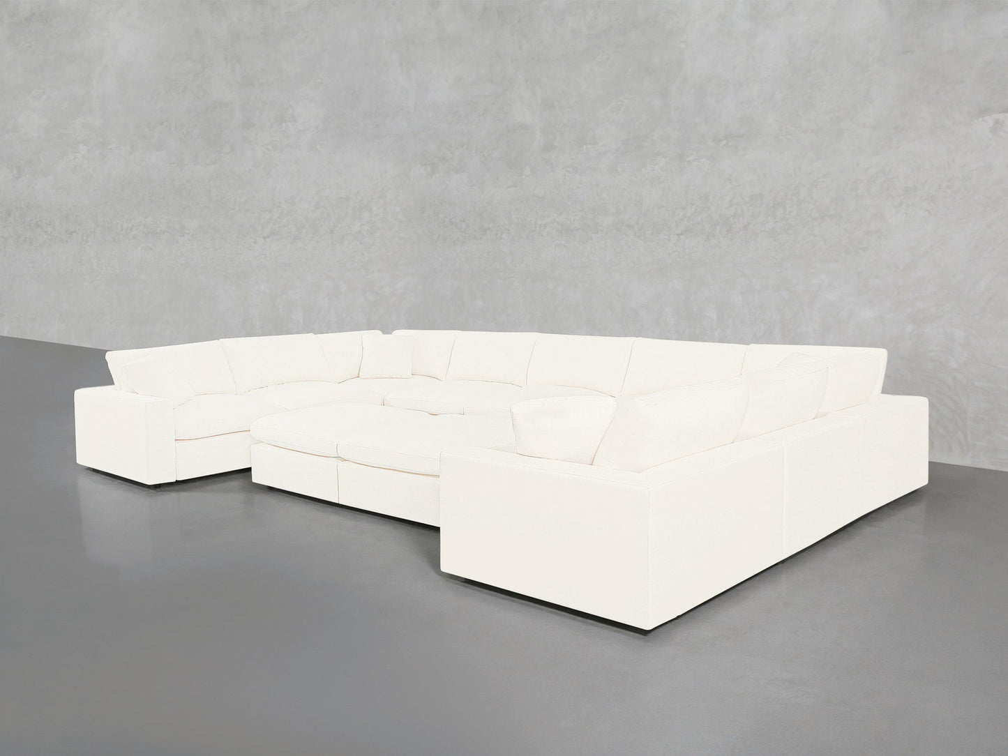 A 9-Seat Modular U-Sectional with Double Ottoman, featuring a modern white design and cushioned seats, sits in a minimalist room with a smooth gray floor and light gray textured walls.
