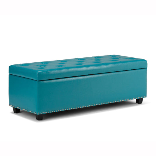 The Hamilton Upholstered Storage Ottoman features a rectangular teal design with a tufted top, silver nailhead trim, and short black legs, shown against a white background.
