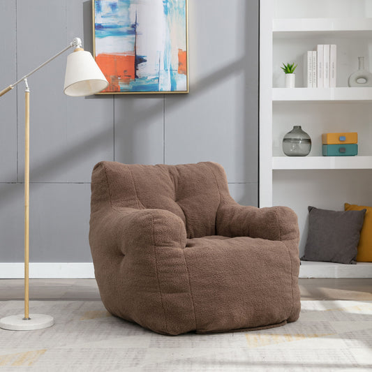 A Soft Teddy Fabric Tufted Foam Bean Bag Chair sits on a light rug in a modern living room, complemented by a floor lamp, abstract wall art, and shelves displaying books, plants, and decorative pieces in the background.