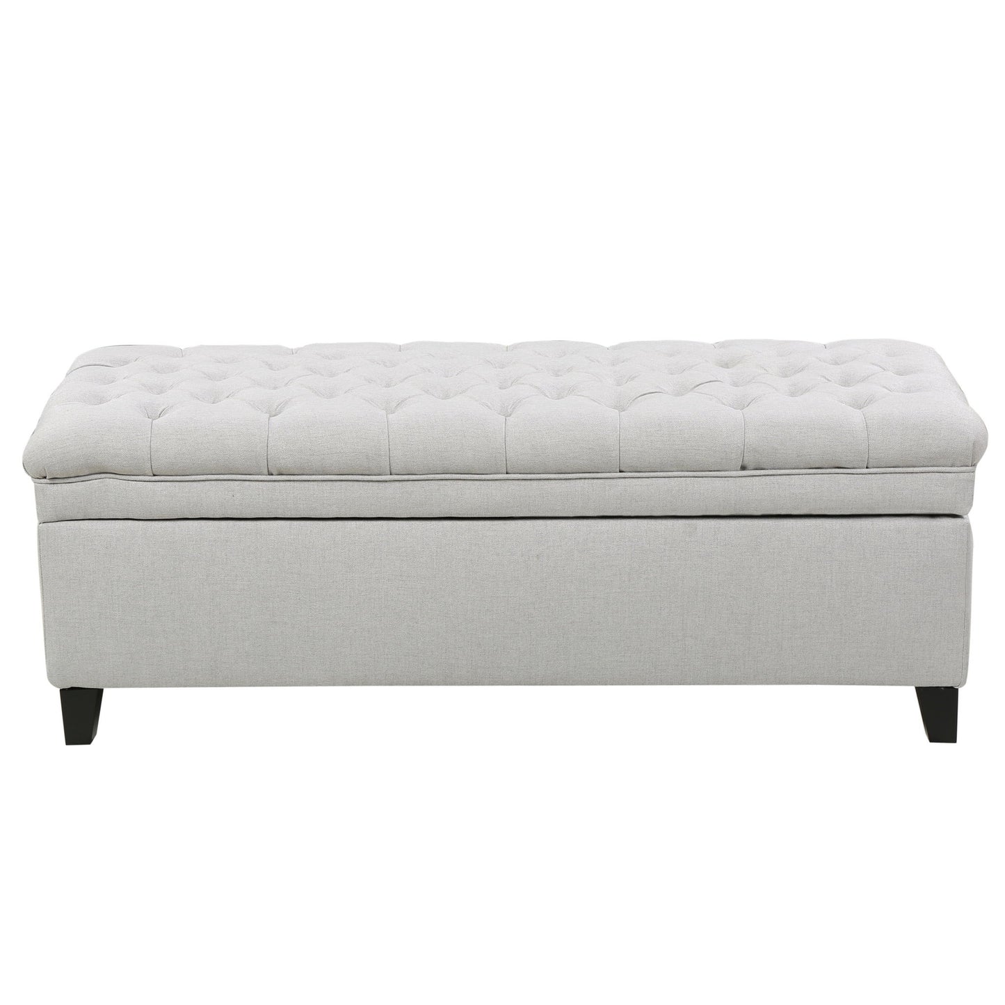 The Juliana Storage Ottoman features a light gray tufted cushioned top and dark birch legs, displayed against a plain white background.