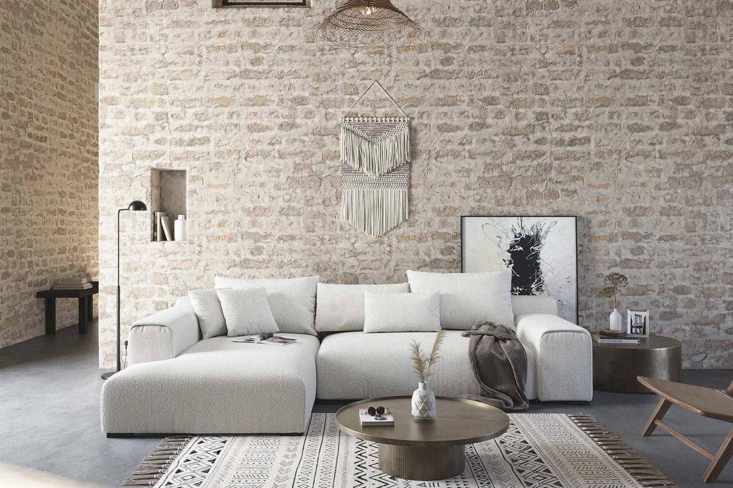 White L-shaped sectional in a large brick room with a circular coffee table in front of it.