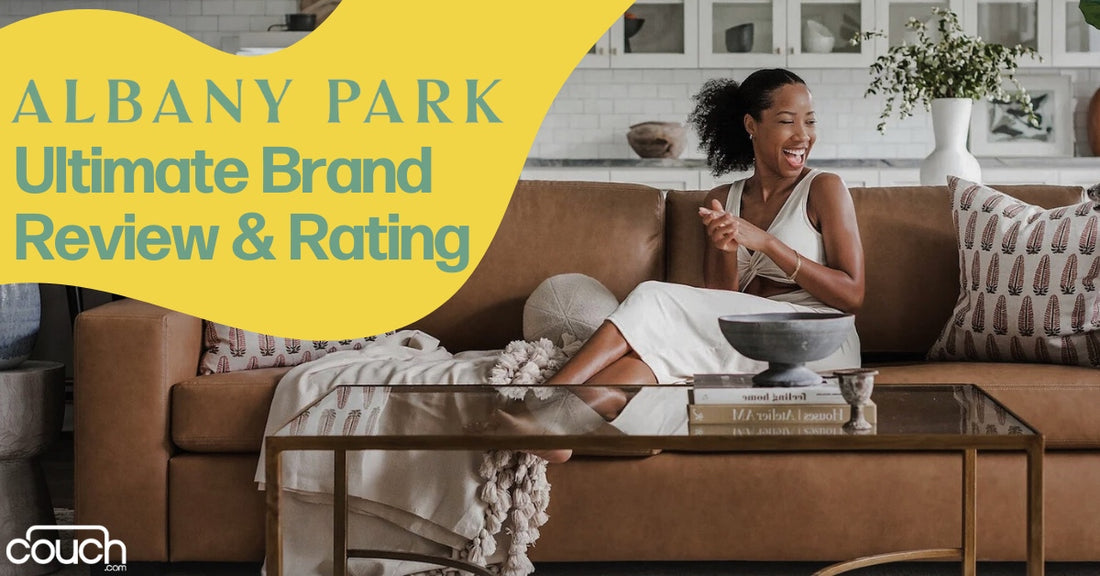A person in a white dress sits on a brown sofa, smiling and clapping. The room features a modern coffee table, a potted plant, and decorative pillows. Text reads "Albany Park Ultimate Brand Review & Rating.