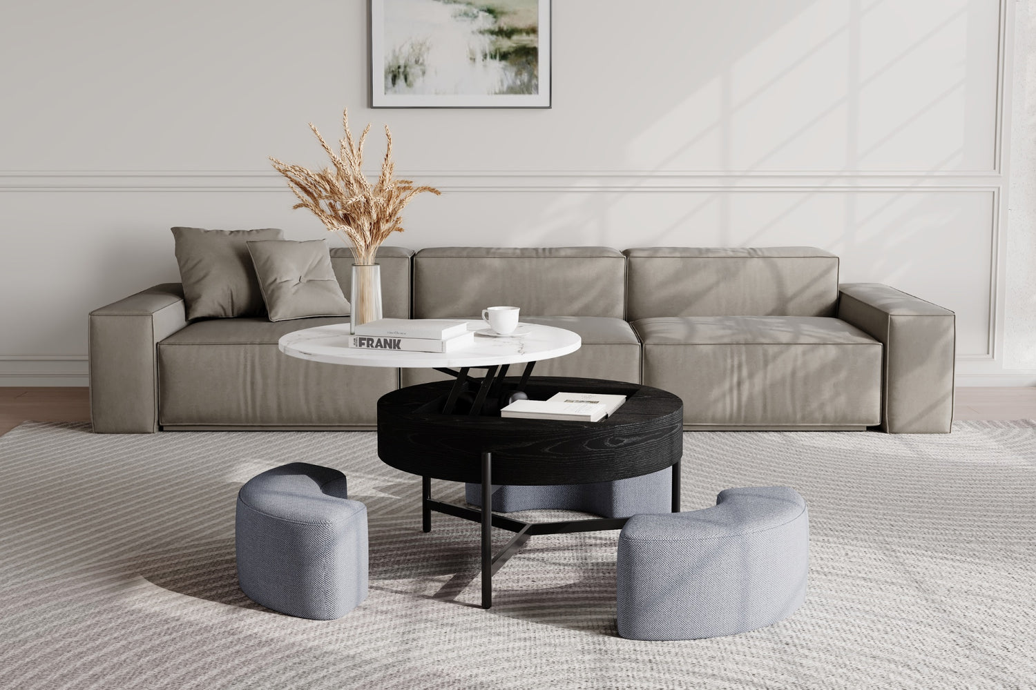 Minimalist living room with a gray sofa, pillows, and a sleek coffee table featuring a white top and black base. Three curved, gray stools surround the table. A framed abstract painting and decorative dried grasses add an artistic touch.