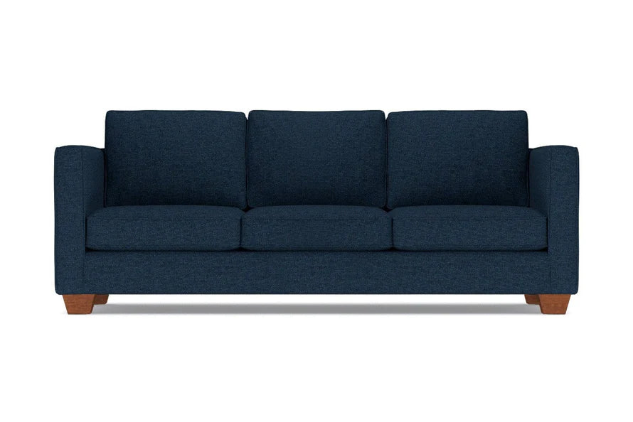 The Catalina Sofa, featuring a dark blue color, is a three-seater with square armrests and wooden legs, shown from the front against a white background.