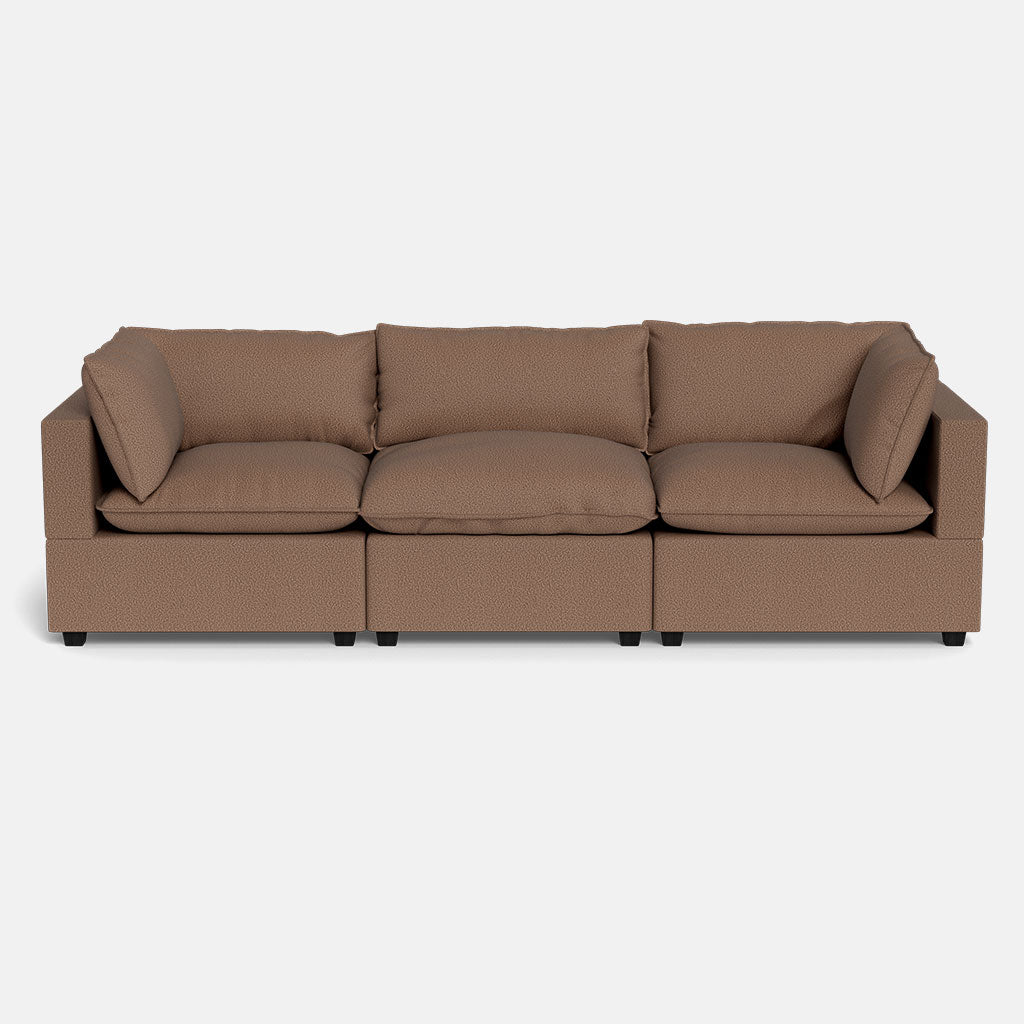 The Kova Pillow Cushion Sofa 122" is a brown, three-seater with rectangular armrests, three seat and back cushions, two side pillows, and is displayed against a plain white background.