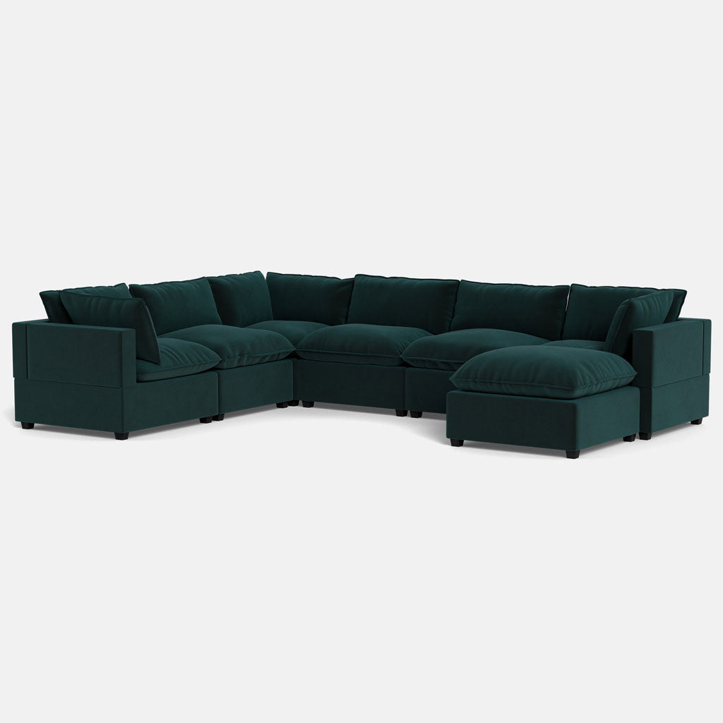 The Kova Pillow Cushion Grand Corner + Ottoman is a large dark green sectional with plush cushions and a right-side chaise, arranged L-shaped on a light background.