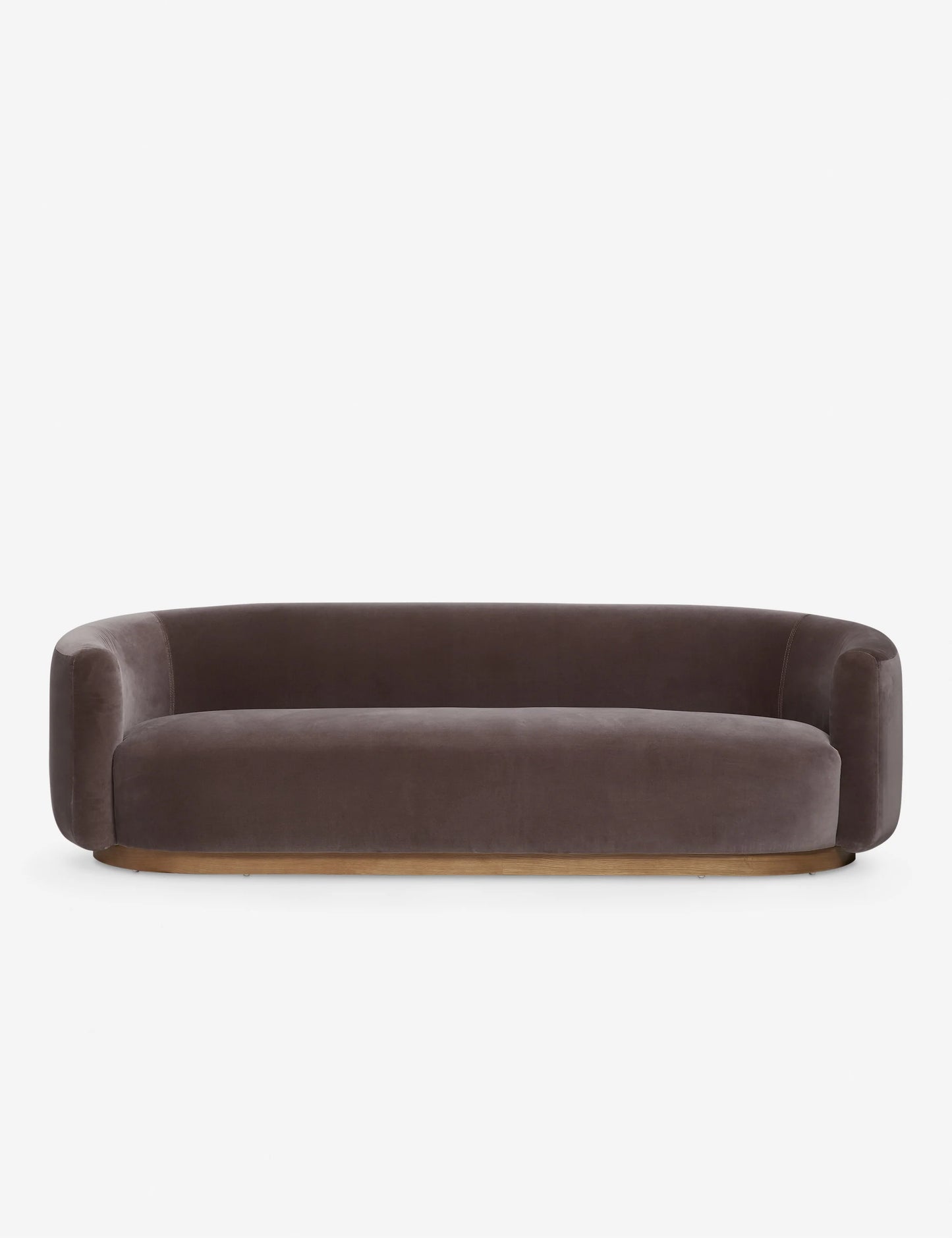 The Lowry Sofa is a stylish piece with its dark gray velvet upholstery, rounded arms, and low backrest. Set against a plain white background, it boasts a sleek, minimalist design with a wooden base that gives it an elegant and contemporary appearance.