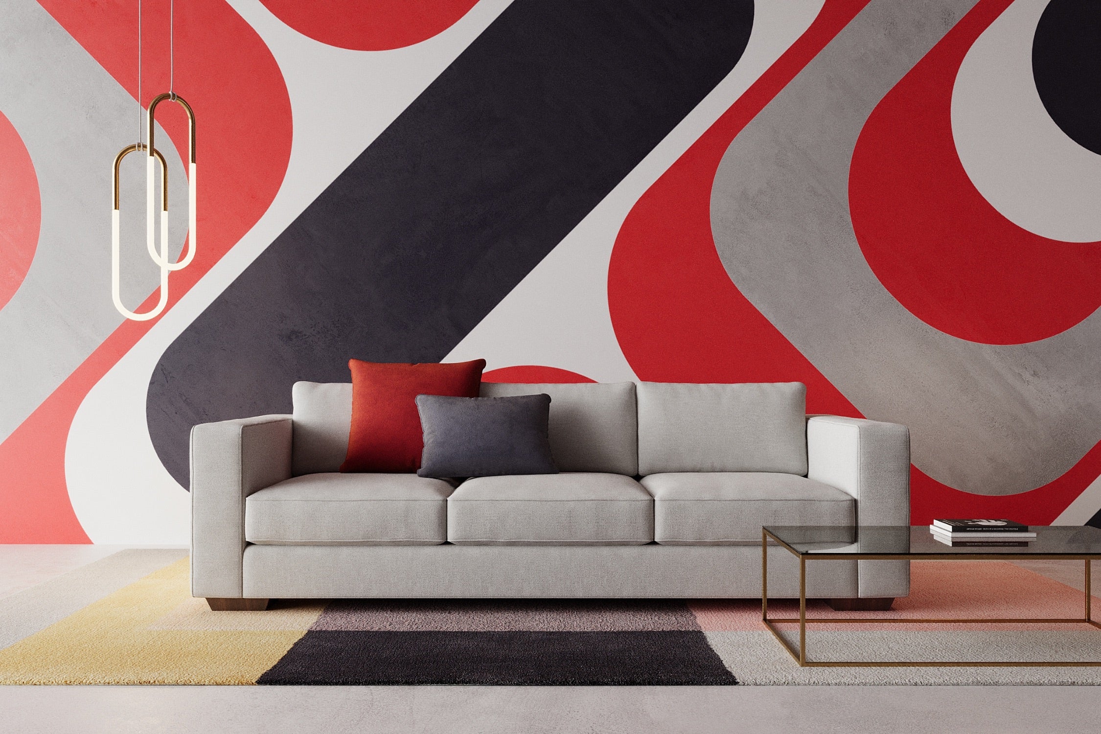 Modern living room featuring a light gray sofa with one red and one gray pillow. The background has a bold red, black, and gray geometric pattern. A glass coffee table and stylish pendant lights complete the decor.