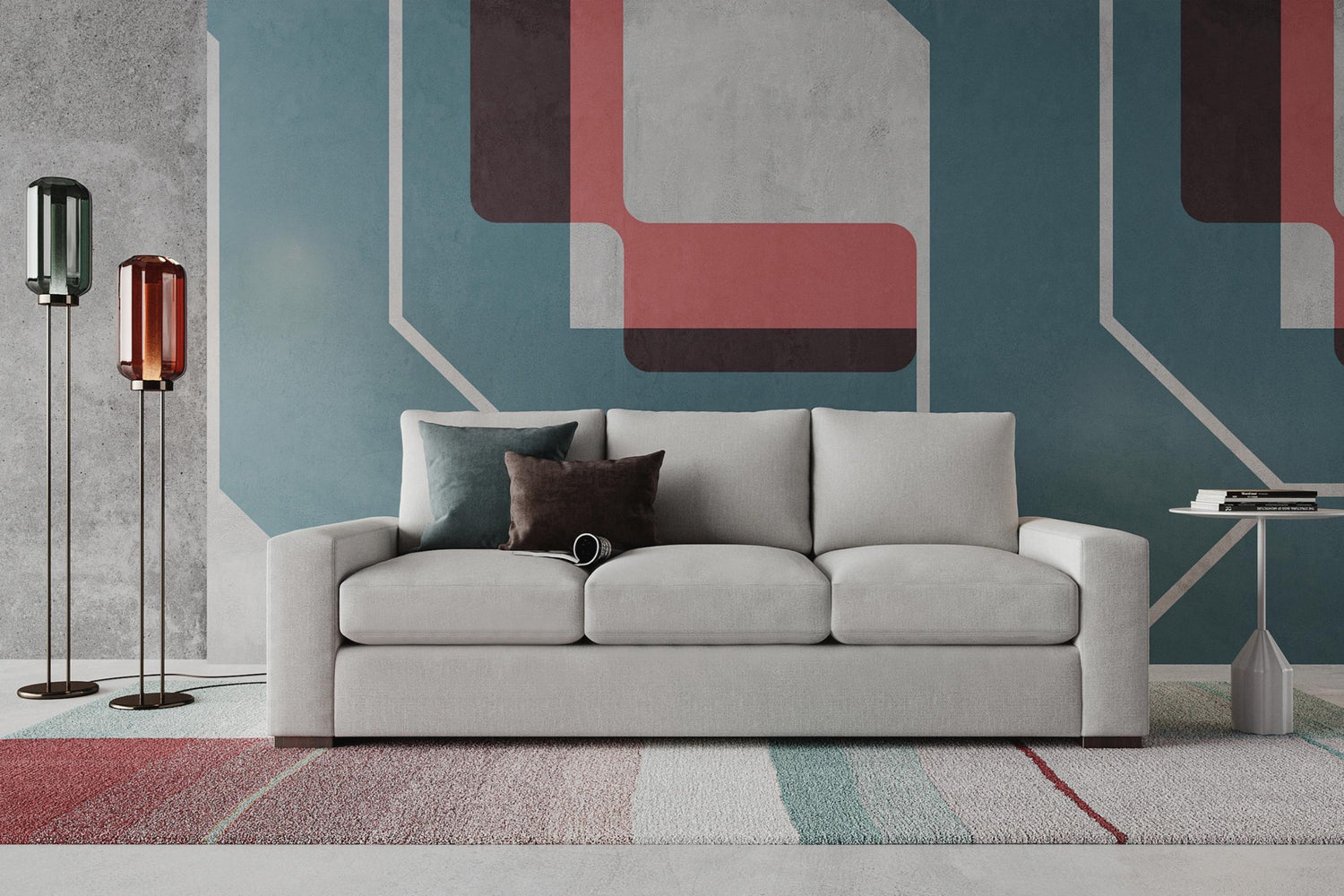 A modern living room features a light gray sofa with a dark cushion. A pair of tall, stylish floor lamps stand on the left. The wall has a geometric pattern in teal, red, and gray tones. A colorful rug is on the floor, and a small table is on the right.