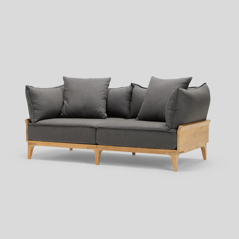 Introducing the Bluff Loveseat: a contemporary gray fabric sofa crafted with a wooden frame and legs. It features three cushioned back pillows and embodies a minimalist design, all set against a plain light gray backdrop.