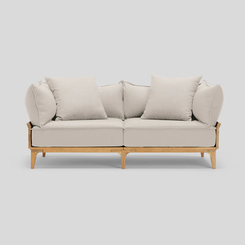 The Bluff Loveseat is a beige, two-seater sofa featuring wooden legs and comes with four matching cushions set against a light gray background.