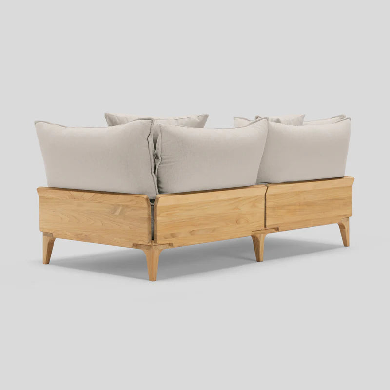 The Bluff Loveseat is a sectional sofa with a wooden frame, featuring light beige cushions and a minimalist design, showcased from the back against a light gray background.
